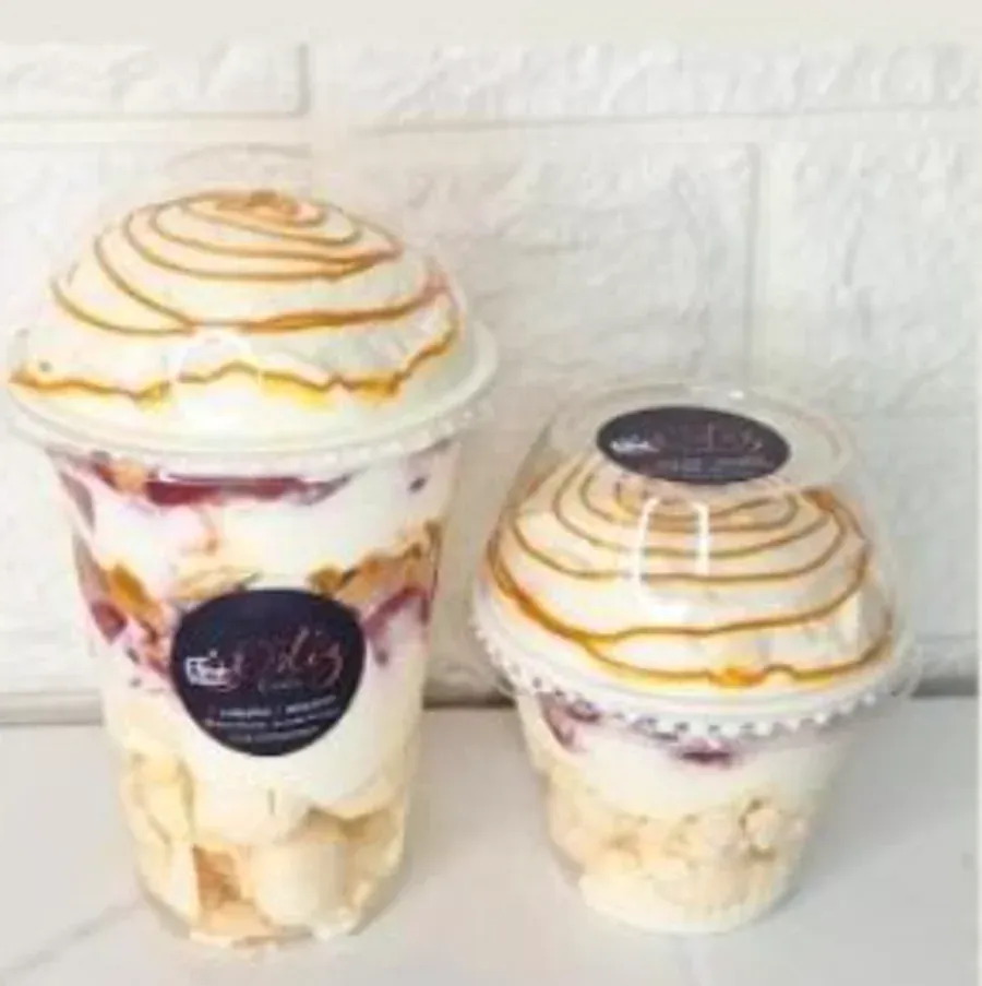 Un vaso grande y un vaso mediano de merengue con crema, fruta y caramelo