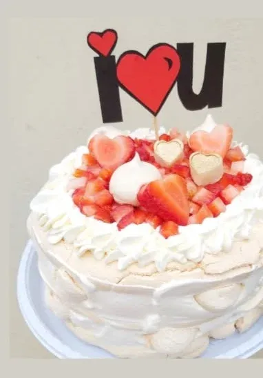 Torta de merengue con frutillas y un cartel decorativo de 'I love u' sobre la torta